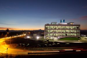 Edificio vetrato illuminato al tramonto con l’insegna Tesisquare sul tetto