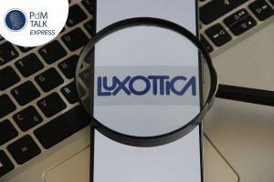 Logo Luxottica osservato con una lente d'ingrandimento, immagine di copertina della puntata di PdM Talk Express sul passaggio generazionale in EssilorLuxottica