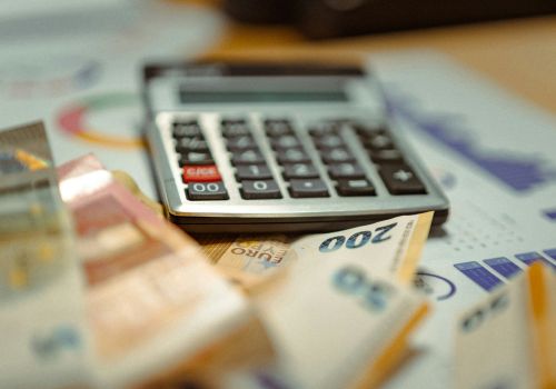 Calcolatrice e banconote in euro appoggiate su fogli con grafici e tabelle finanziarie